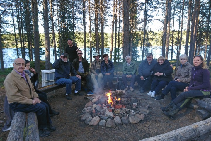 A group of people sitting around a campfire in a forest.