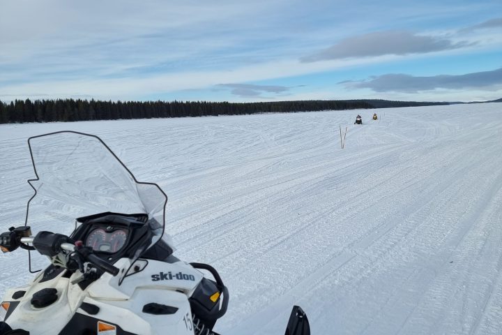 Snowmobile on a snow-covered field with two distant vehicles.