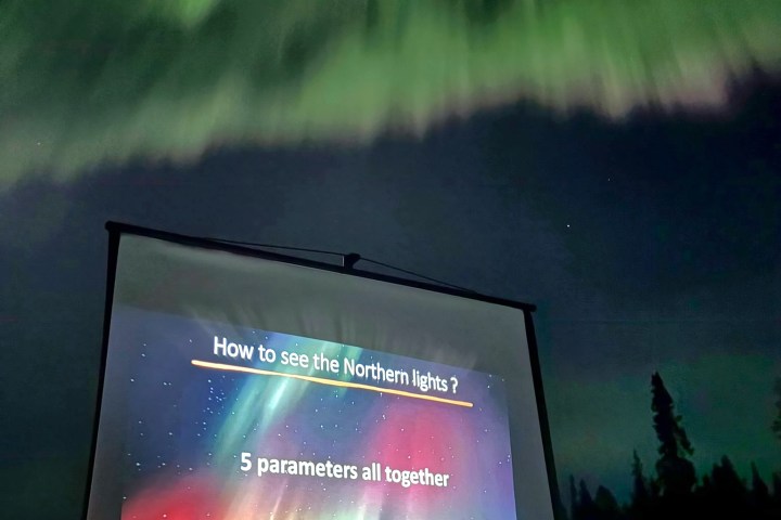 Projection on screen outdoors under green aurora showing tips to see Northern Lights.