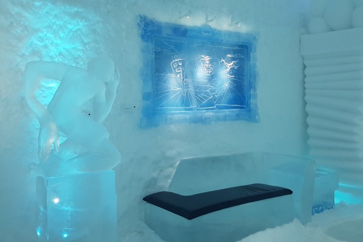 Ice sculpture room with a thinker statue, ice couch, and blue illuminated wall art.