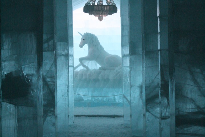 Ice hallway with chandelier and unicorn sculpture at the end.