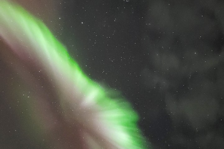 Green aurora borealis in night sky filled with stars.