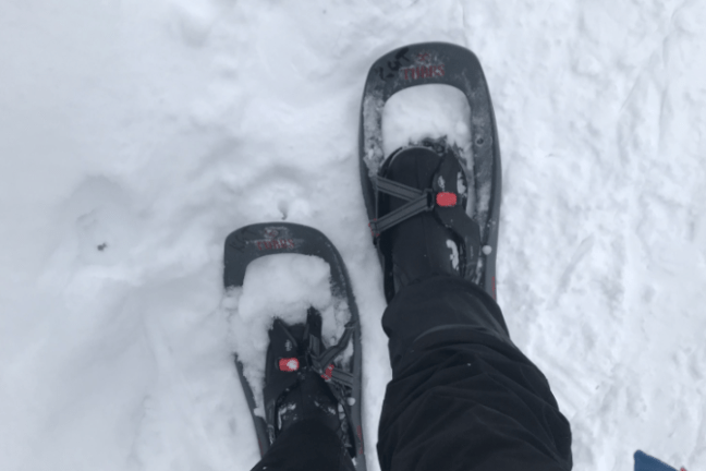 Person wearing snowshoes on a snowy surface, view from above.