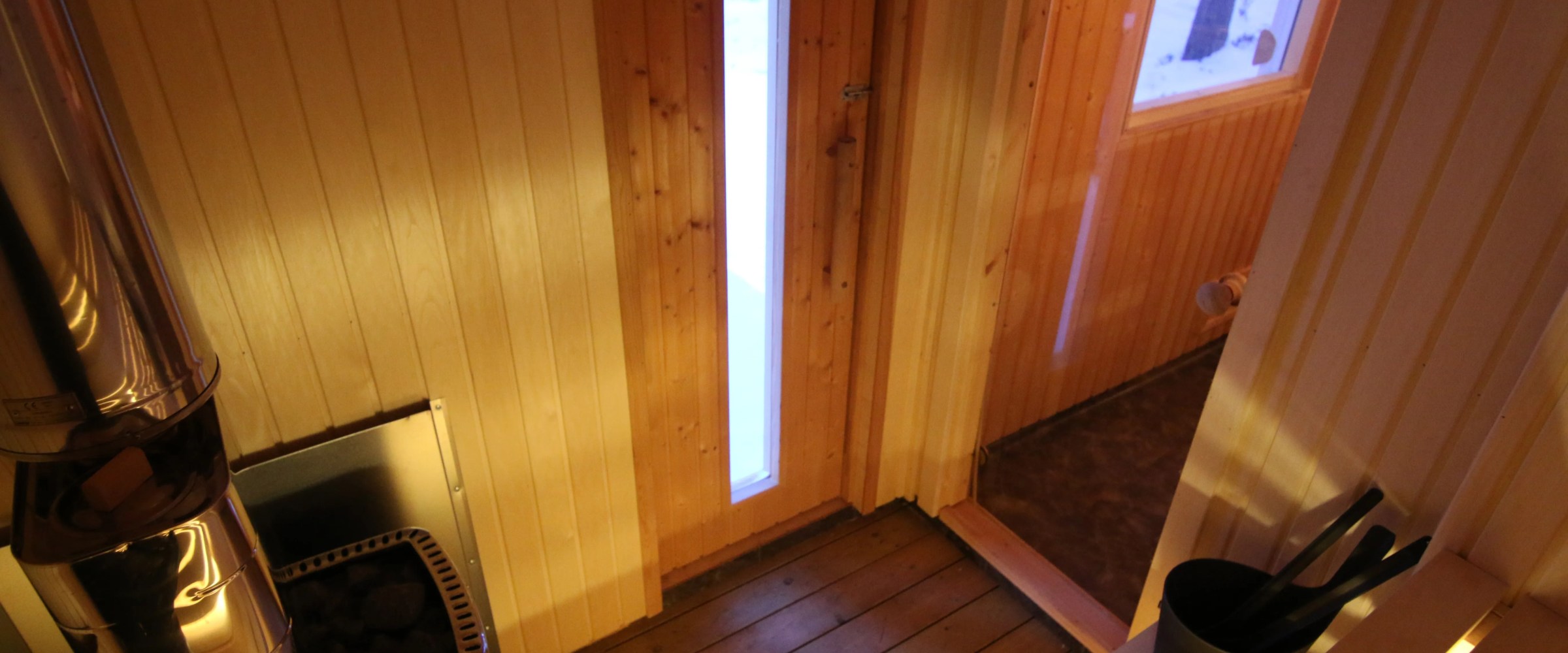 Interior of a wooden sauna with a stove and bucket inside.