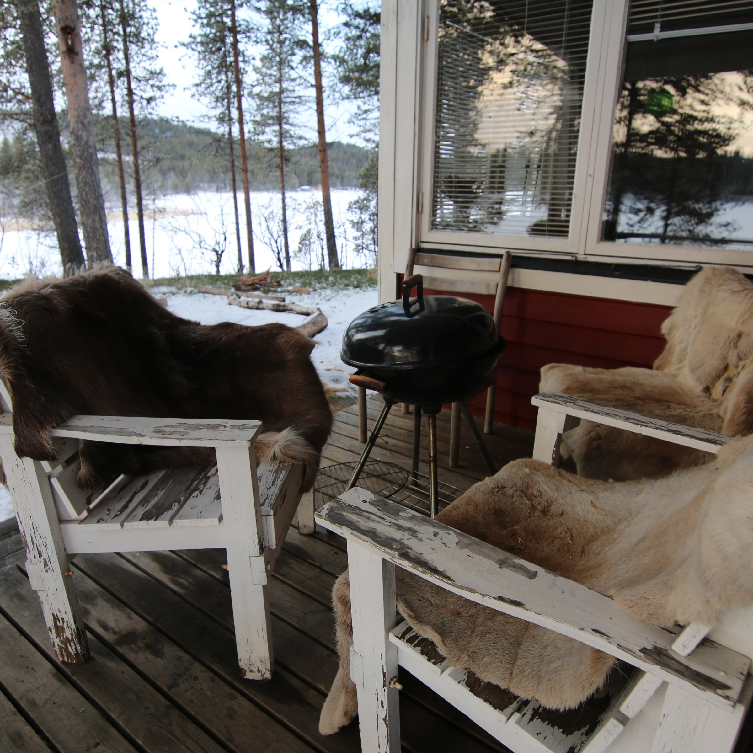 Outdoor deck with two fur-covered chairs, a grill, and snowy landscape view.