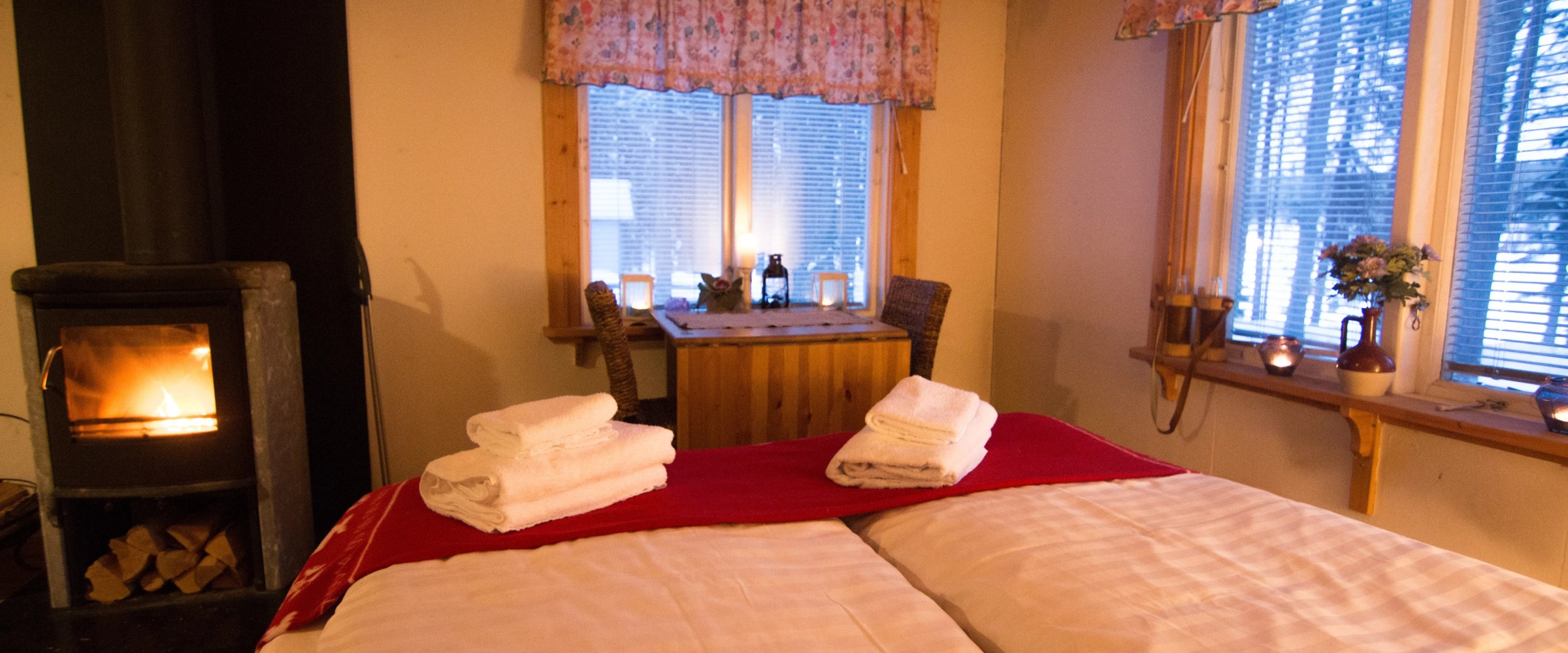 Cozy bedroom with a fireplace, twin beds, and a window view with trees.