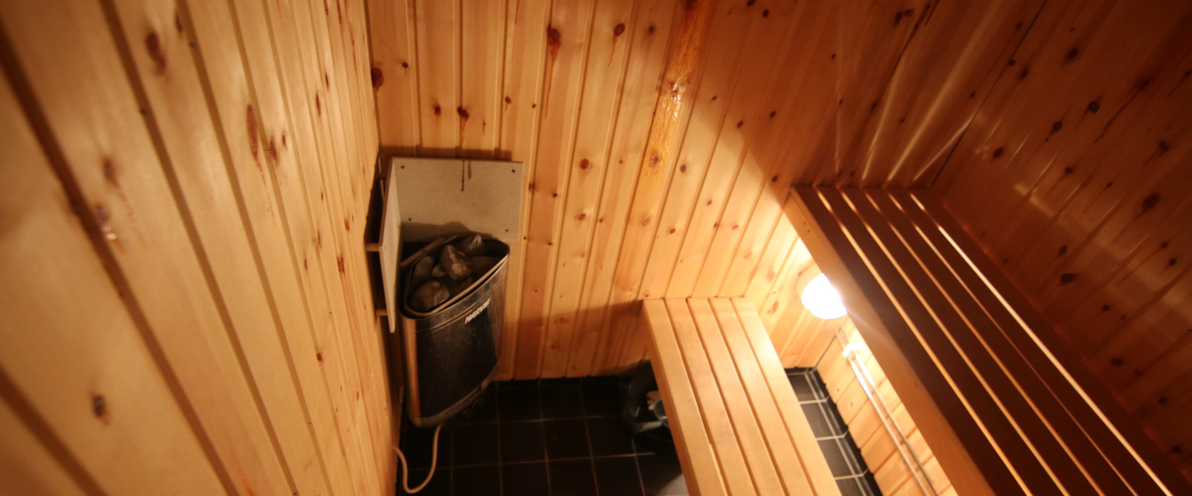 Wooden sauna interior with benches and a heater.