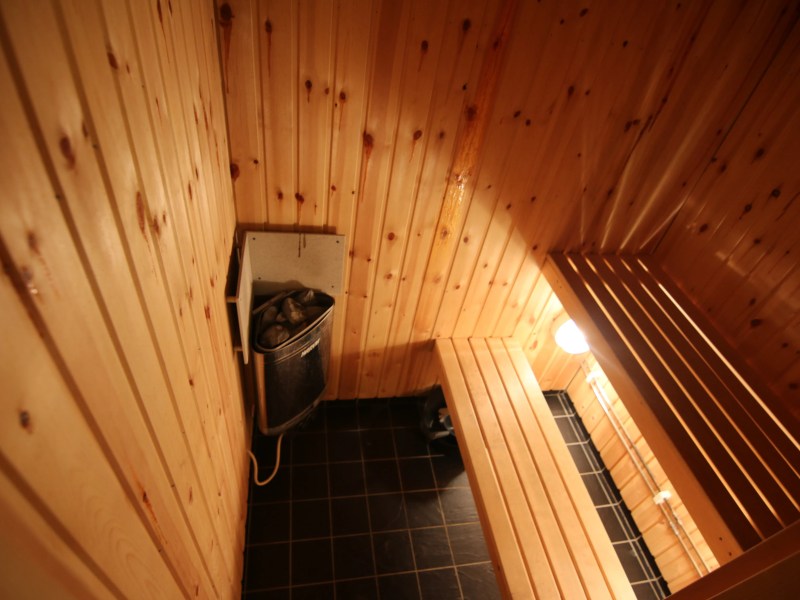 Wooden sauna interior with benches and a heater.