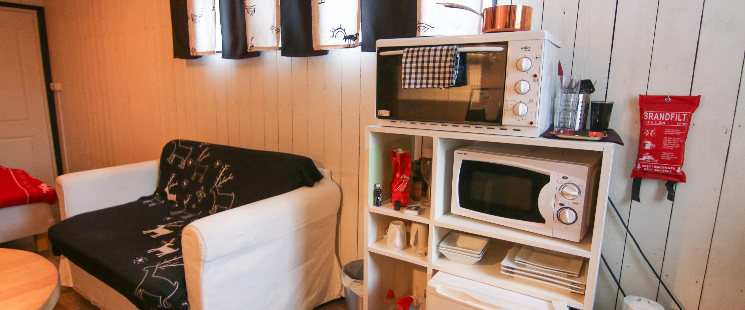 Cozy room with a white sofa, small kitchen area, and minimalistic decor.