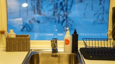 Kitchen sink with soap dispensers, basket, and a window showing snowy scene outside.