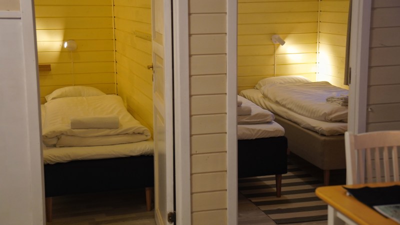 Two small bedrooms with single beds, wooden walls, and soft lighting.