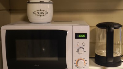Microwave with tea tin on top and electric kettle on the side.