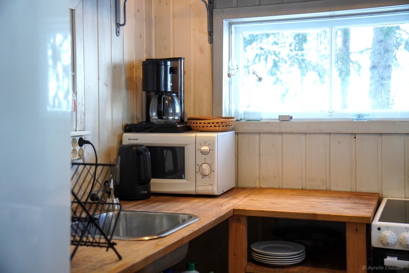 Cozy kitchen with a coffee maker, microwave, and kettle on a wooden counter near a window.