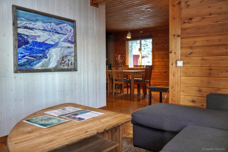 Cozy wooden cabin interior with a painting, table, and chairs.