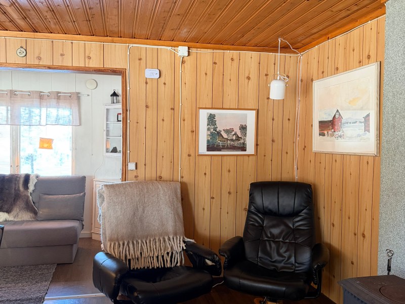 Cozy room with wood paneling, two armchairs, and a fireplace.