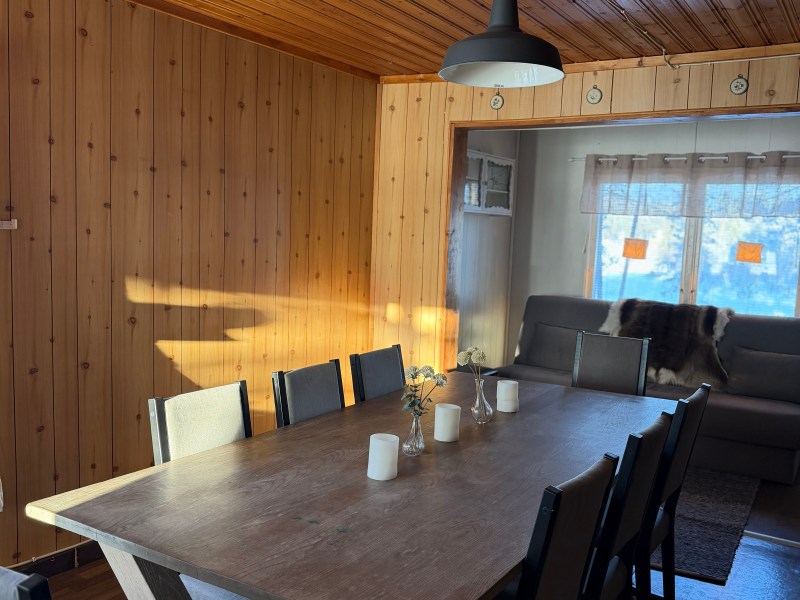 Wood-paneled room with a large dining table, modern chairs, and pendant light.
