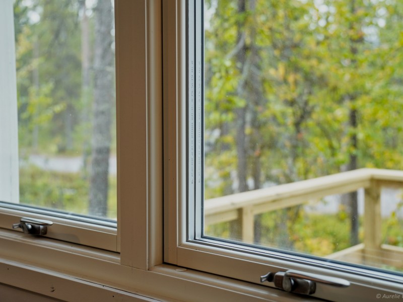 View through a window showing a wooden railing and trees outside.